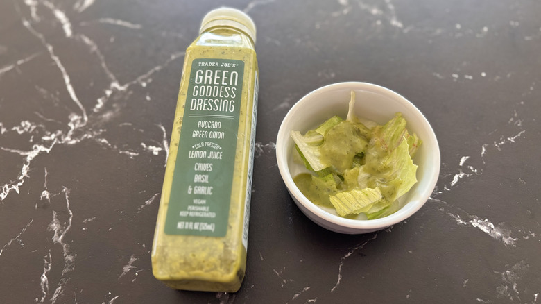Trader Joe's green goddess dressing bottle next to small bowl of salad