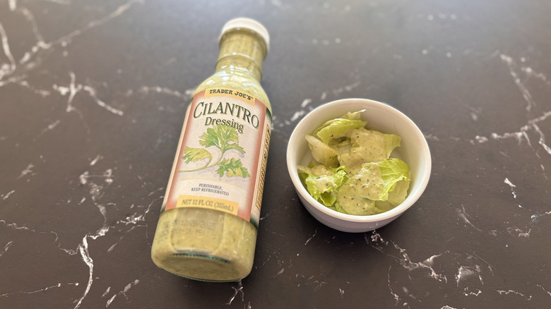 Trader Joe's cilantro dressing bottle next to small bowl of salad