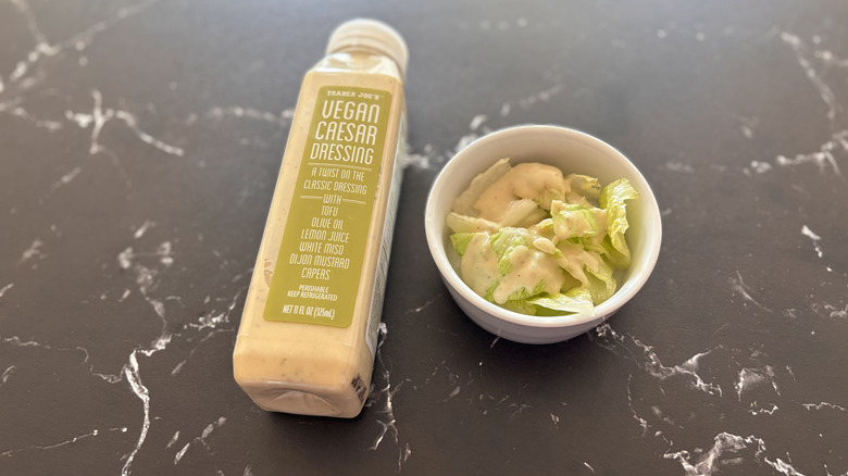 Trader Joe's vegan Caesar dressing bottle next to small bowl of salad