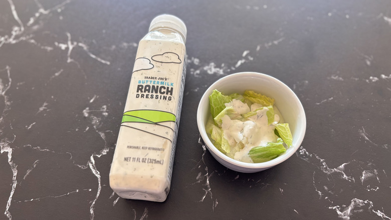 Trader Joe's buttermilk ranch dressing bottle next to small bowl of salad