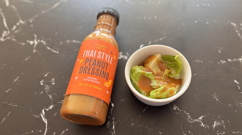 Trader Joe's Thai style peanut dressing bottle next to small bowl of salad