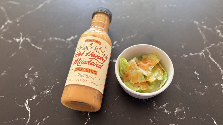 Trader Joe's hot honey mustard dressing bottle next to small bowl of salad