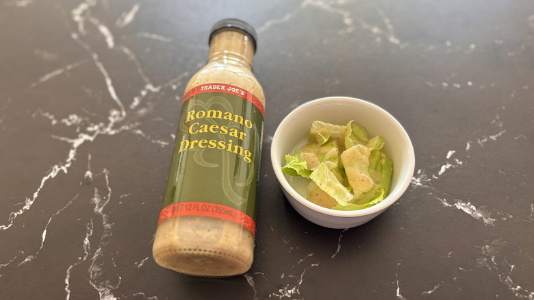 Trader Joe's Romano Caesar dressing bottle next to small bowl of salad