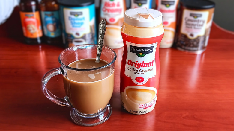 Glass mug of coffee with cream next to container of Clover Valley original non-dairy coffee creamer.