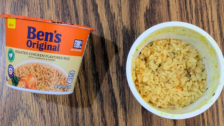 A top view of yellow rice in a plastic cup next to a sealed cup of Ben's Original Roasted Chicken Flavored rice