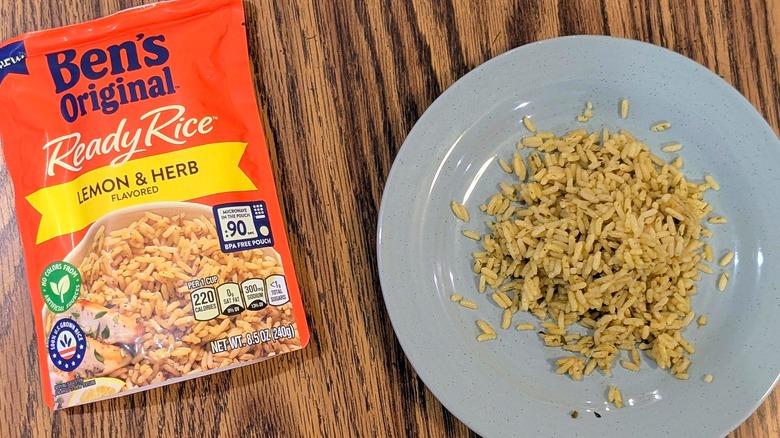Yellow rice on a light blue plate next to an orange pouch of Ben's Original Lemon & Herb rice