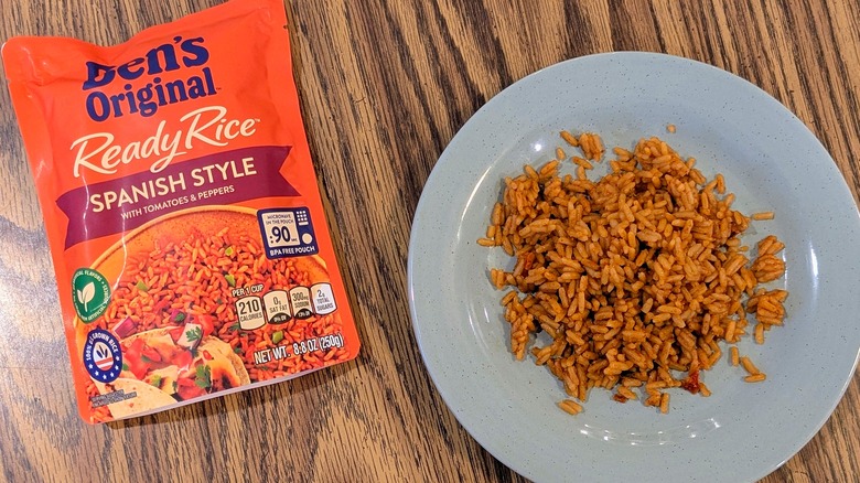 Orange rice on a light blue plate next to an orange pouch of Ben's Original Spanish rice
