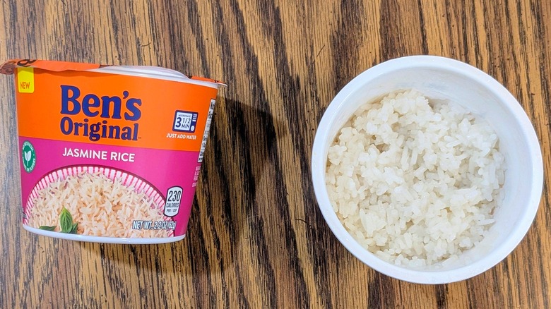 A top view of white rice in a palstic cup nexct to a sealed cup of Ben's Original jasmine rice