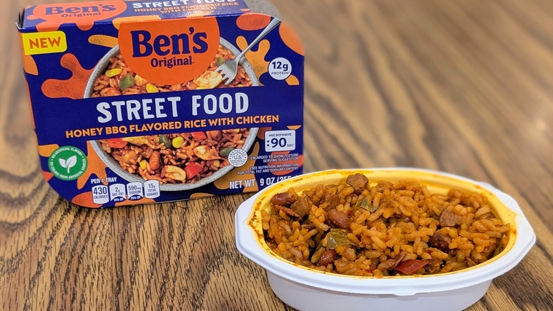 A brown rice dish in a white plastic container next to a conatiner of Ben's Original Streed Food Honey BBQ Rice