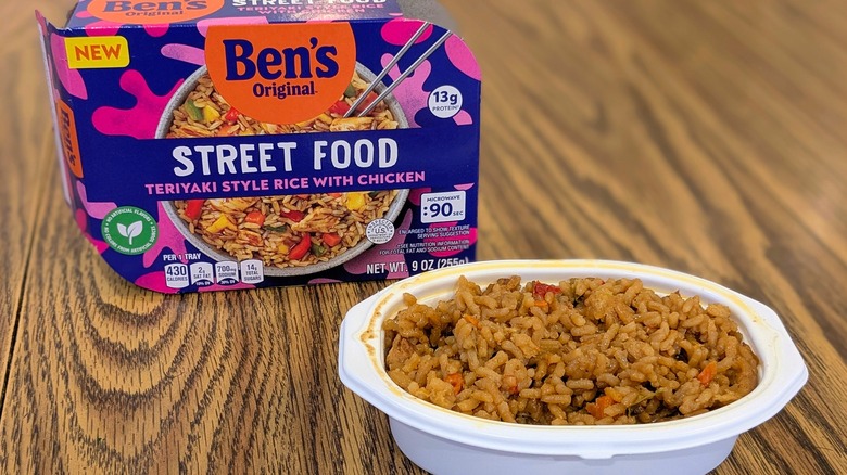Brown teriyaki rice in a white plastic container next to a box of Ben's Original Street Food Teriyaki Rice