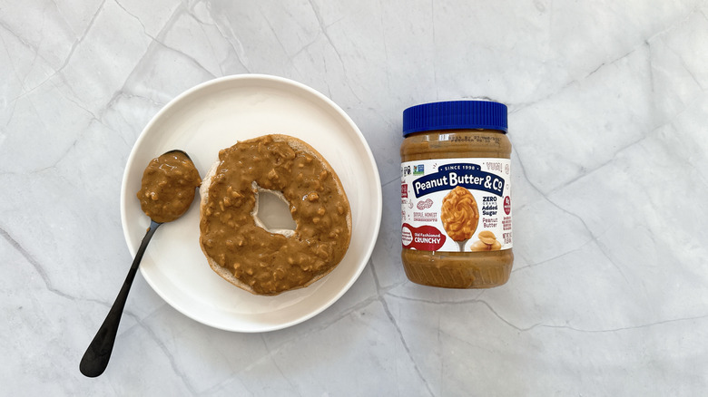 Peanut butter on a bagel and jar of Peanut butter & Co