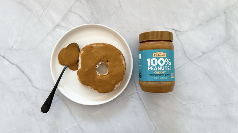 Peanut butter on a bagel and jar of Crazy Richard's