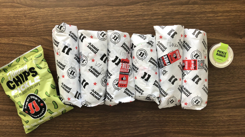 Six Jimmy John's Picklewiches in their wrappers side by side with pickle chips and pickle ranch.
