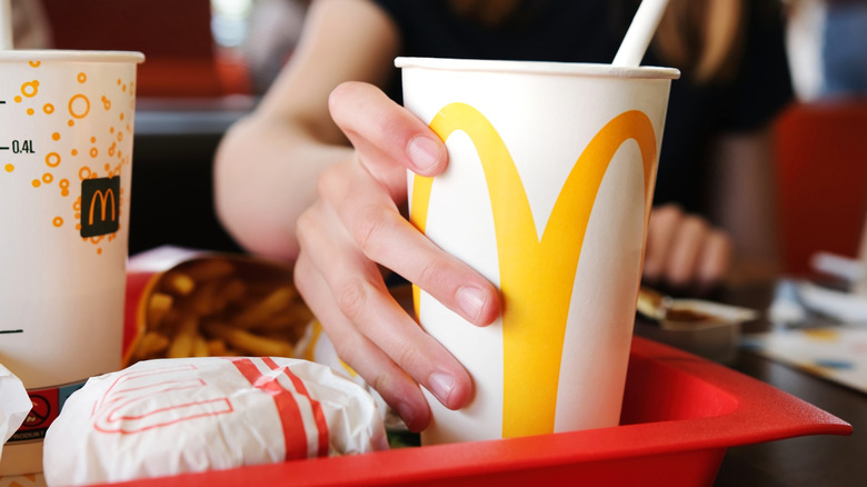 hand reaching for McDonald's soda cup on food tray