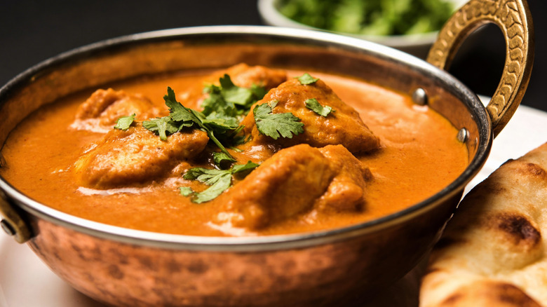 butter chicken in bowl with naan