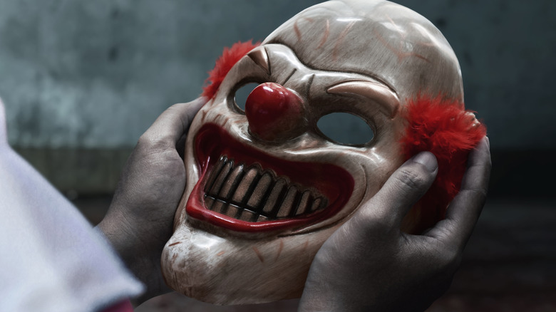Hands holding a scary clown mask