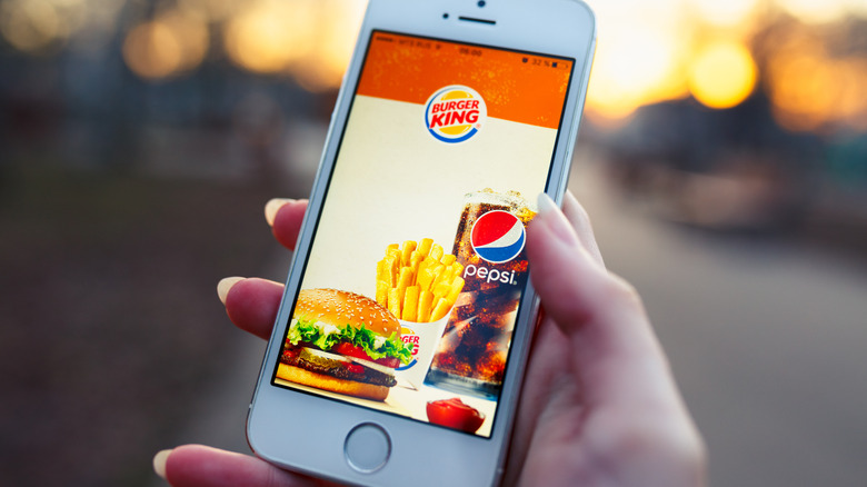 Hand holding phone with Burger King app open