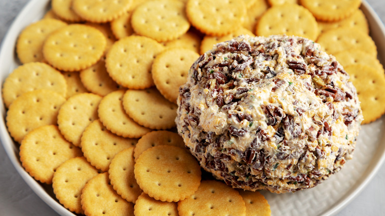 a cheese ball topped with walnuts and accompanied by ritz crackers