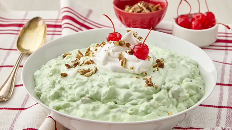 a bowl of watergate salad topped with maraschino cherries