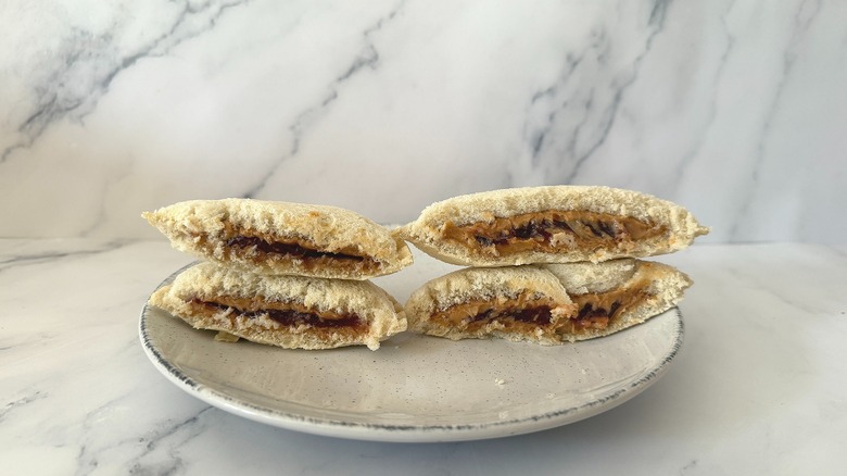 Welch's and Uncrustables sandwiches cut in half, side by side on white plate