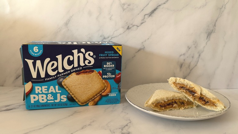 Box of Welch's Real PB&Js next to sandwich cut in half on white plate