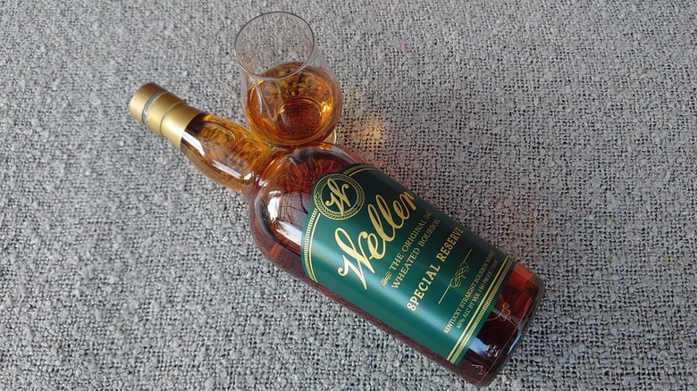 An overhead shot of a bottle of Weller Special Reserve on a blanket next to a filled glass