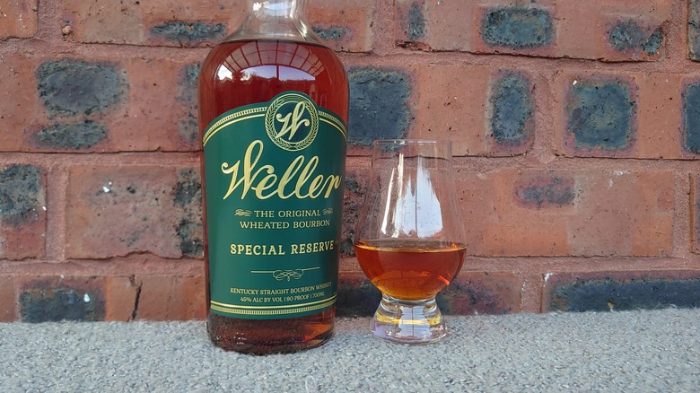 A bottle of Weller Special Reserve in front of a brick background next to a filled Glencairn glass