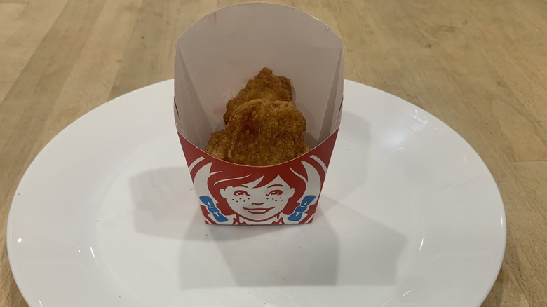 chicken nuggets in cardboard Wendy's container on white plate