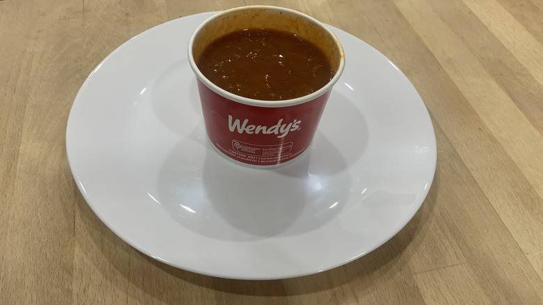 open paper container of chili on white plate