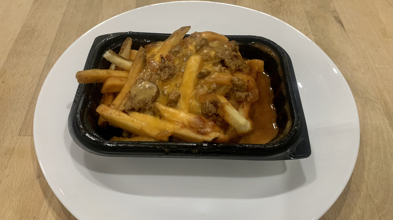 chili cheese fries in plastic container on top of white plate