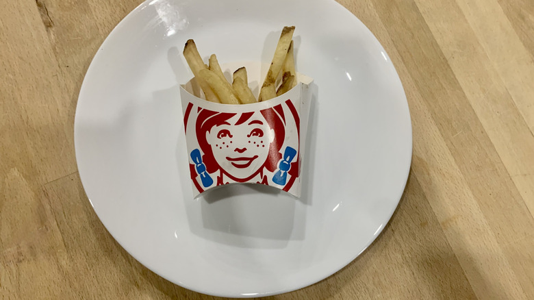 french fries in Wendy's paper container on top of white plate