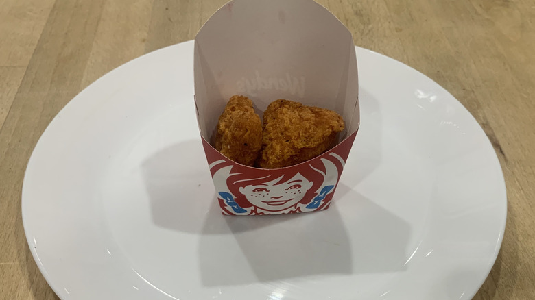 spicy chicken nuggets in cardboard Wendy's container on white plate