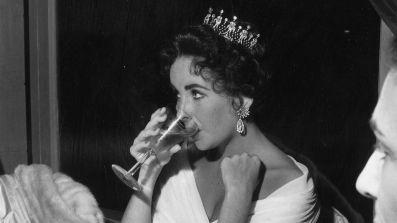 Black and white photo of Elizabeth Taylor sipping drink
