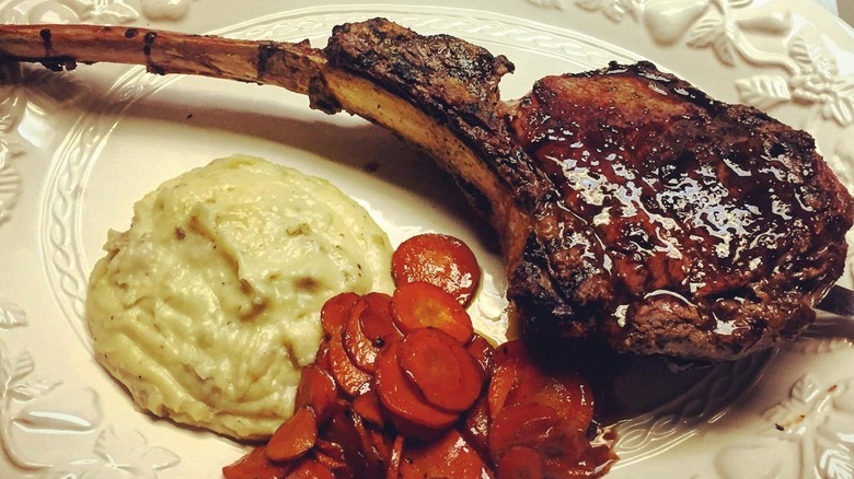 Bone-in steak on plate with mash and carrots