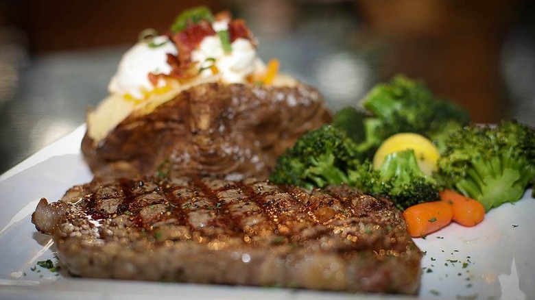 Steak with baked potato and broccoli on plate