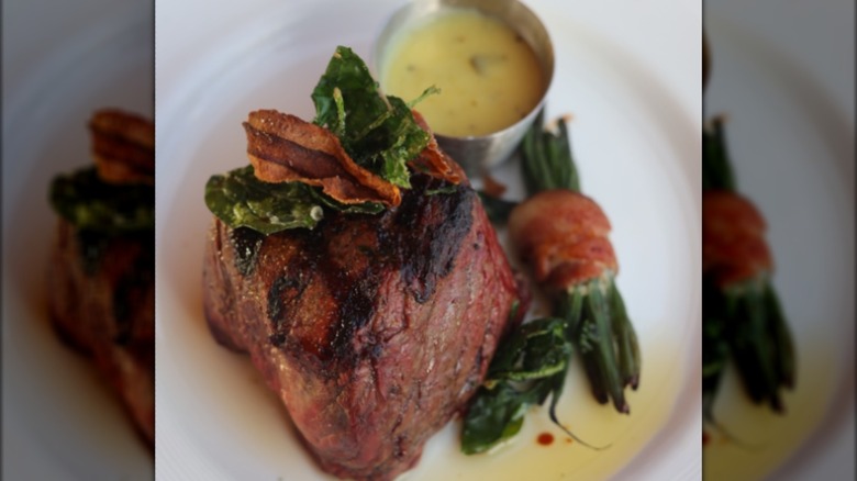 Tpo sirloin filet with greens and dipping sauce on plate
