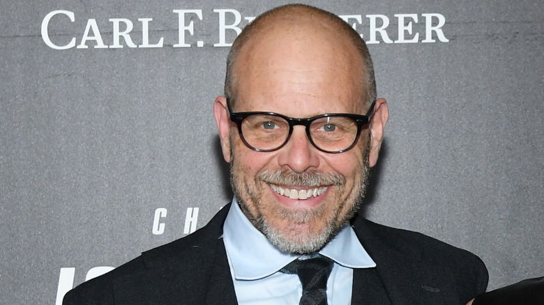 Alton Brown wearing suit and smiling at camera