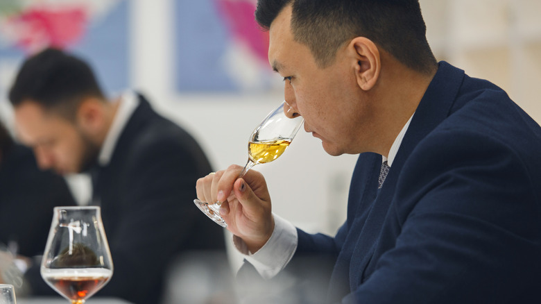 Professional sommelier sniffing whiskey tasting.
