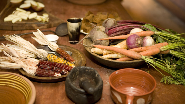 Corn, apples, and root vegetables on table being prepared for dinner