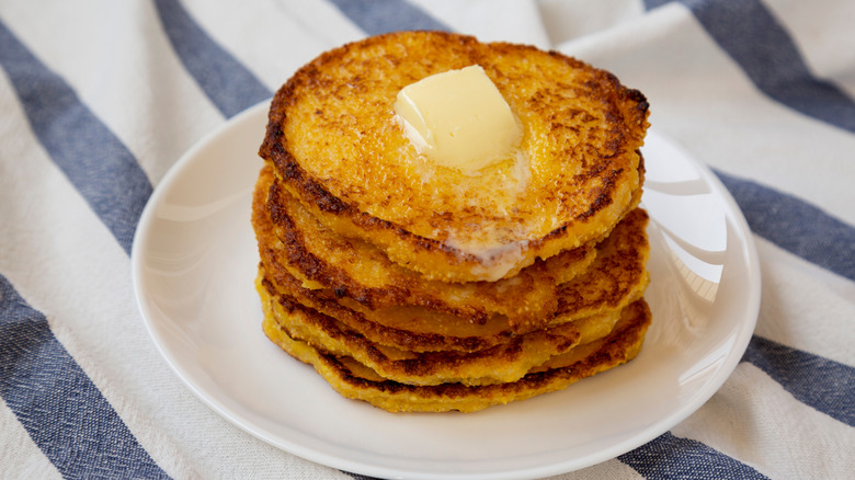 Stack of Johnny cakes on plate, topped with butter