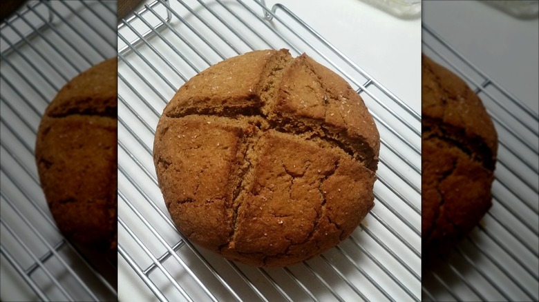 Circular loaf of rye and Indian bread on metal cooling rack