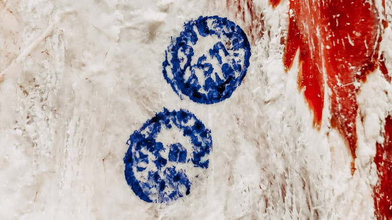 beef carcass with white fat that has been stamped with 2 smudged blue USDA inspection stamps