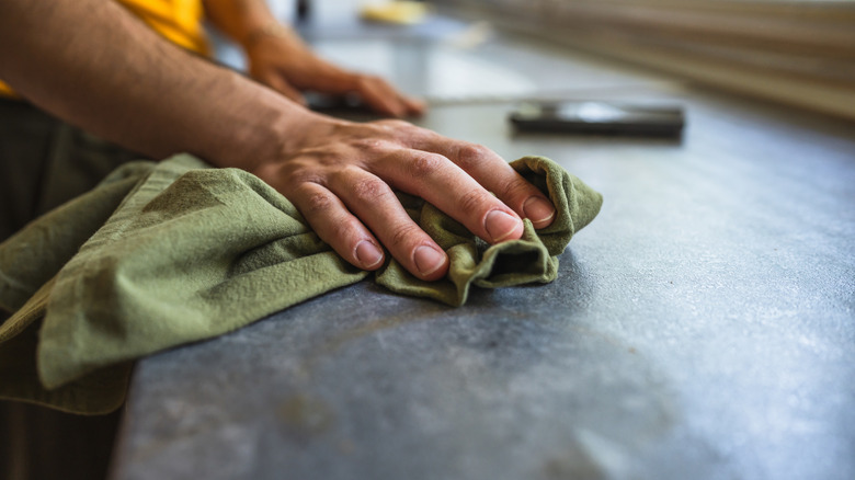 A person wipes down a countertop with a cloth