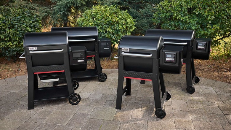 Four black Weber grills lined up on a patio