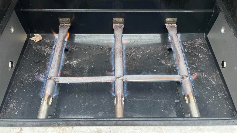A close-up view of lit Weber burners that have very low flames