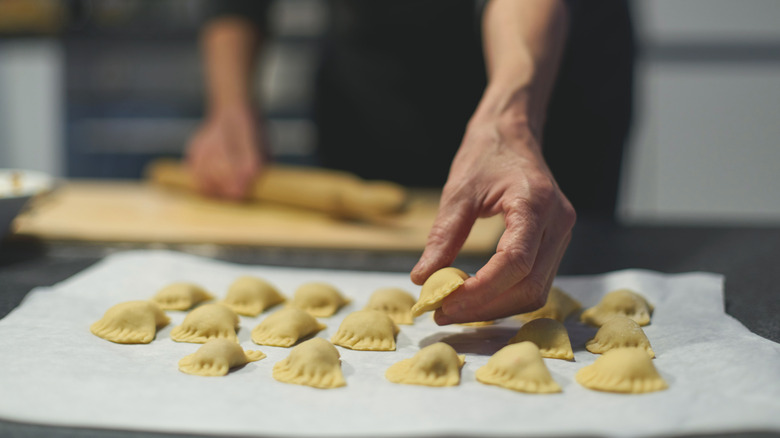 person placing homemade stuffed pasta on a kitchen towel