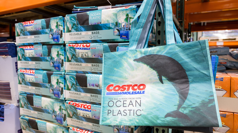 Reusable blue tote bags with dolphin design and Costco Wholesale logo displayed in Costco store