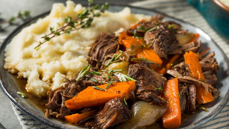 Plate of shredded beef pot roast meat, carrots, and mashed potatoes.