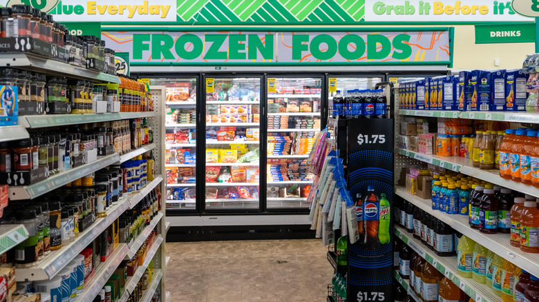 A Dollar Tree aisle full of soft drinks and food that ends in the frozen food coolers