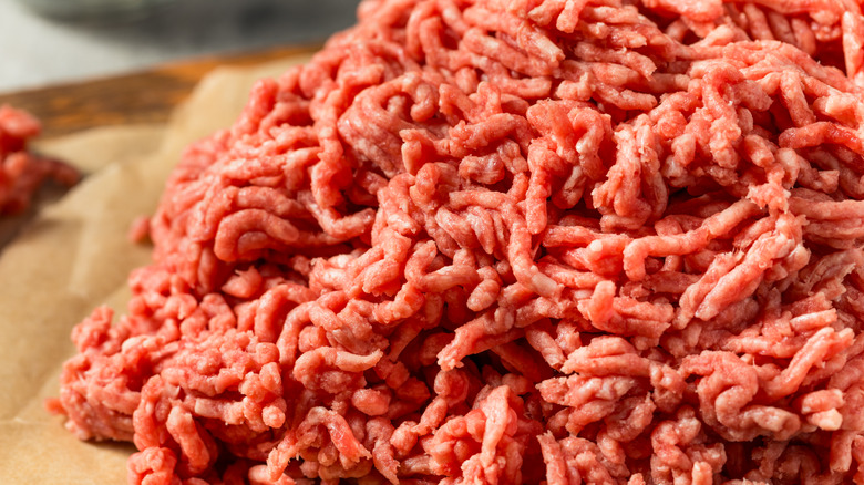 A pile of fresh, pink ground beef sitting on butcher paper